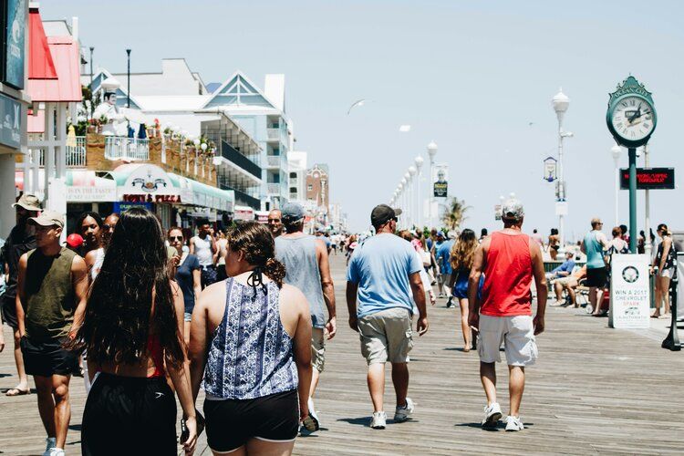 A large group of people are walking down a boardwalk.