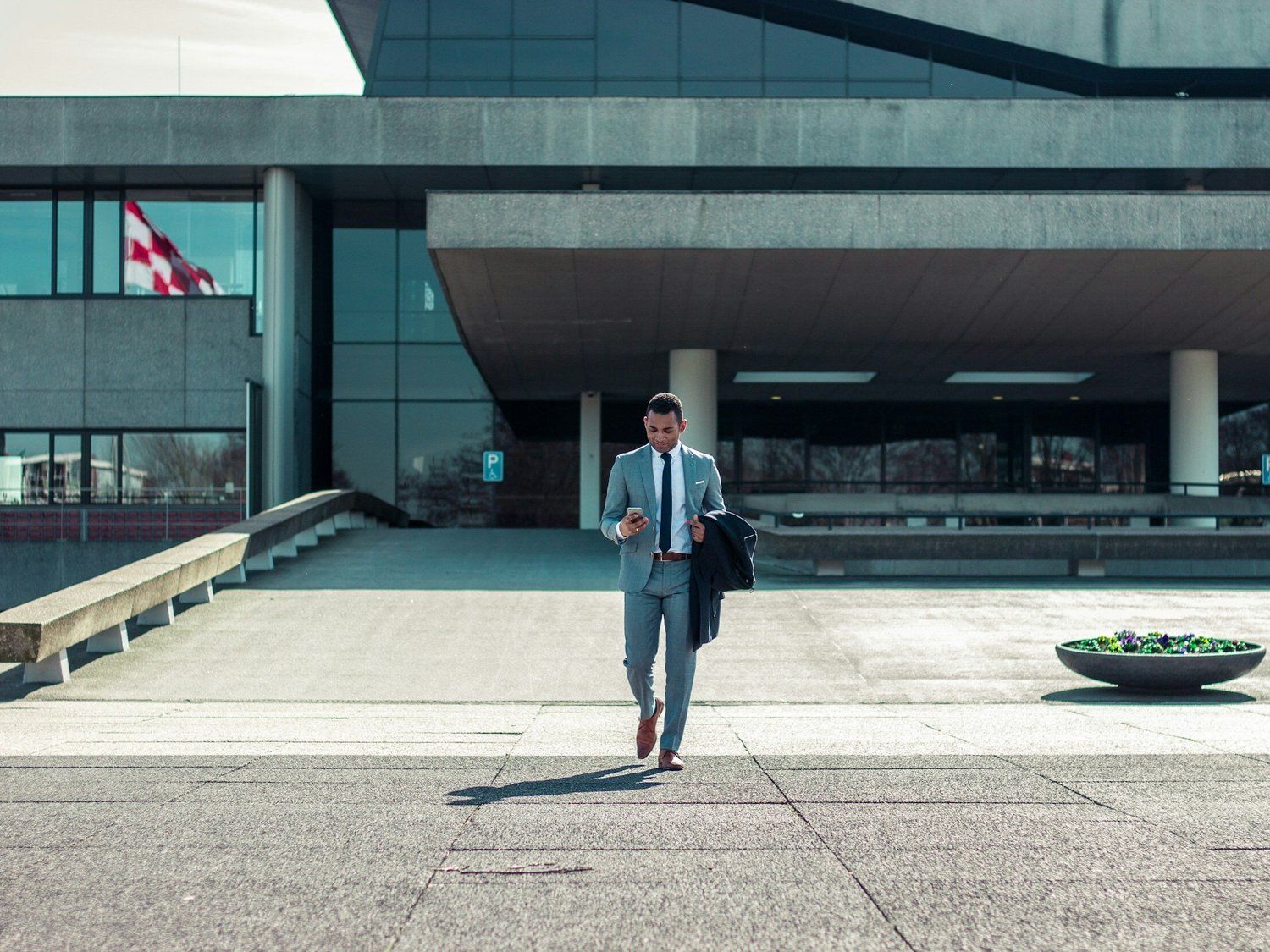 A man in a suit and tie is walking in front of a building.