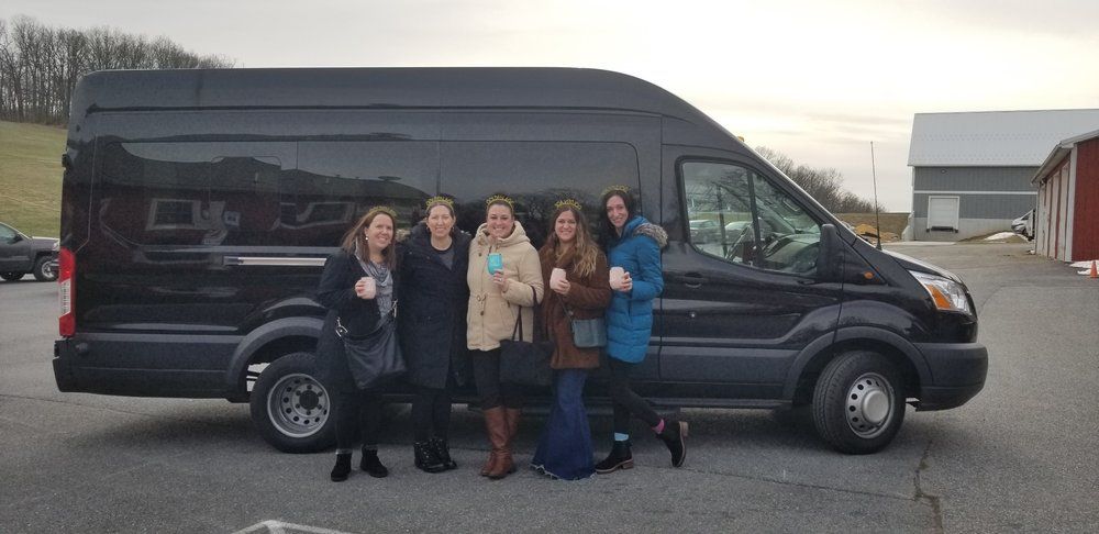 A group of women are standing in front of a black van.