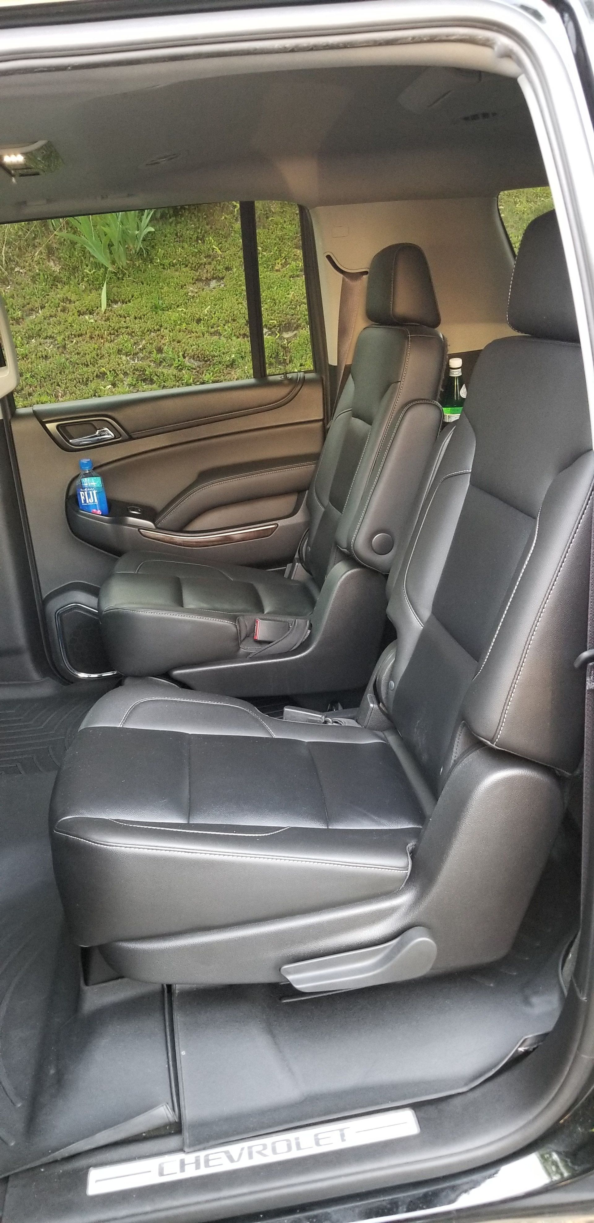 The back seat of a black suv with the door open.