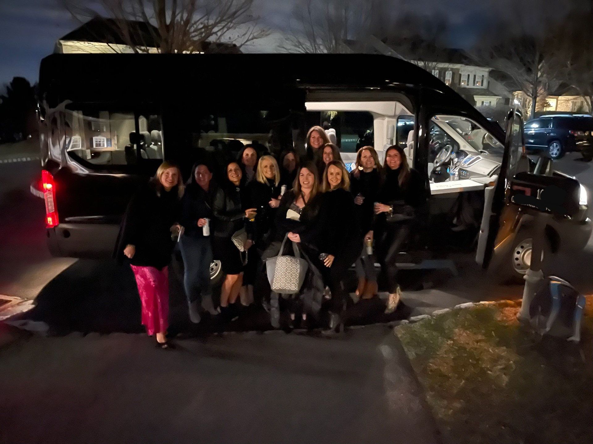 A group of women are standing in front of a truck at night.