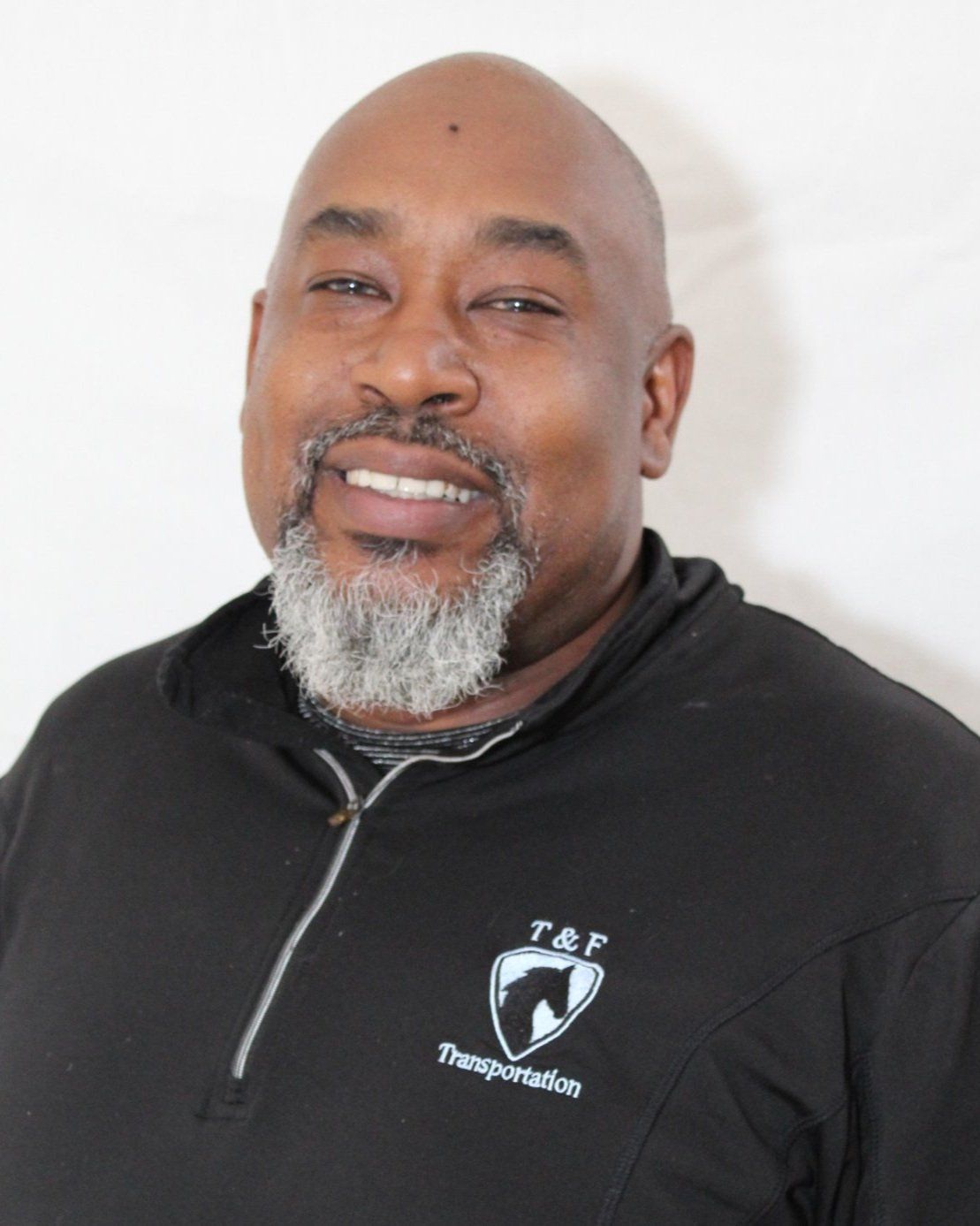 A man with a beard is wearing a black shirt that says t & p transportation