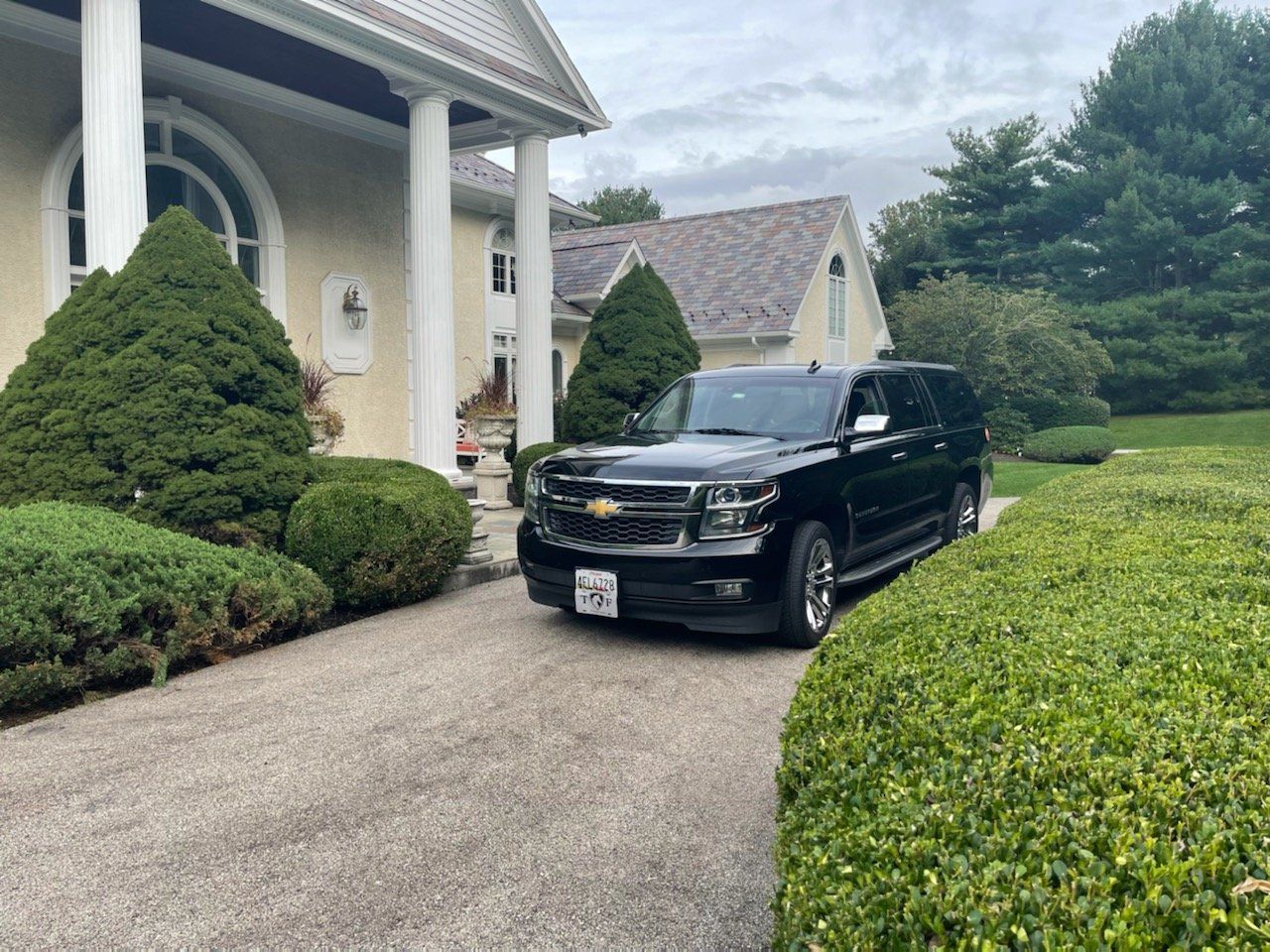 A black suv is parked in front of a large house.