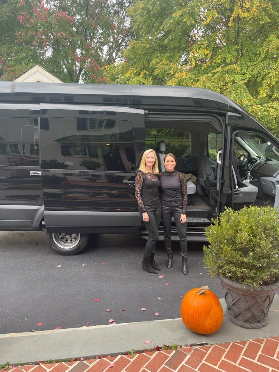 Two women are standing in front of a black van.