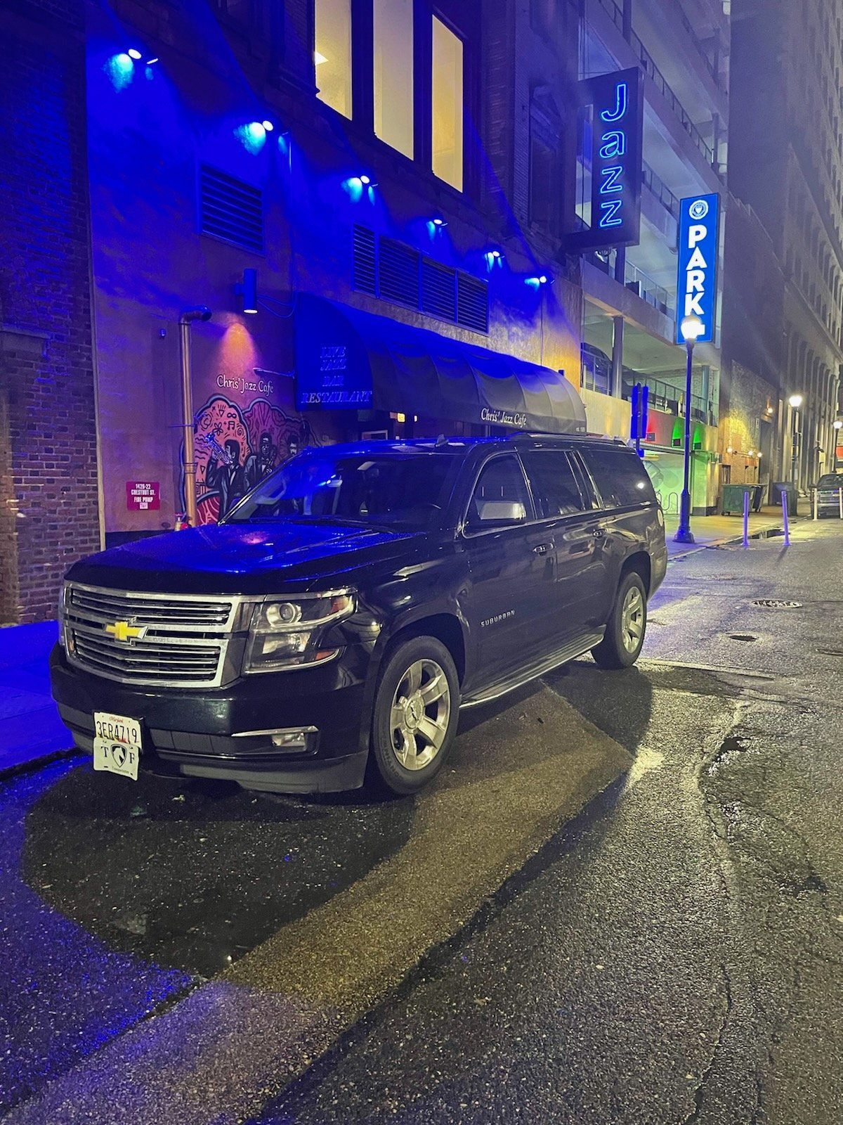 A black suv is parked on the side of the road in front of a building.