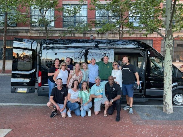 A group of people are posing for a picture in front of a van.