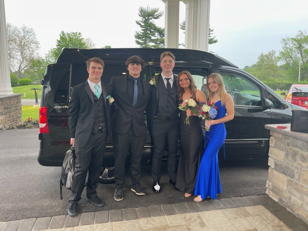 A group of people standing in front of a black van.