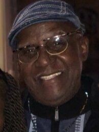 A man wearing glasses and a hat is smiling for the camera.