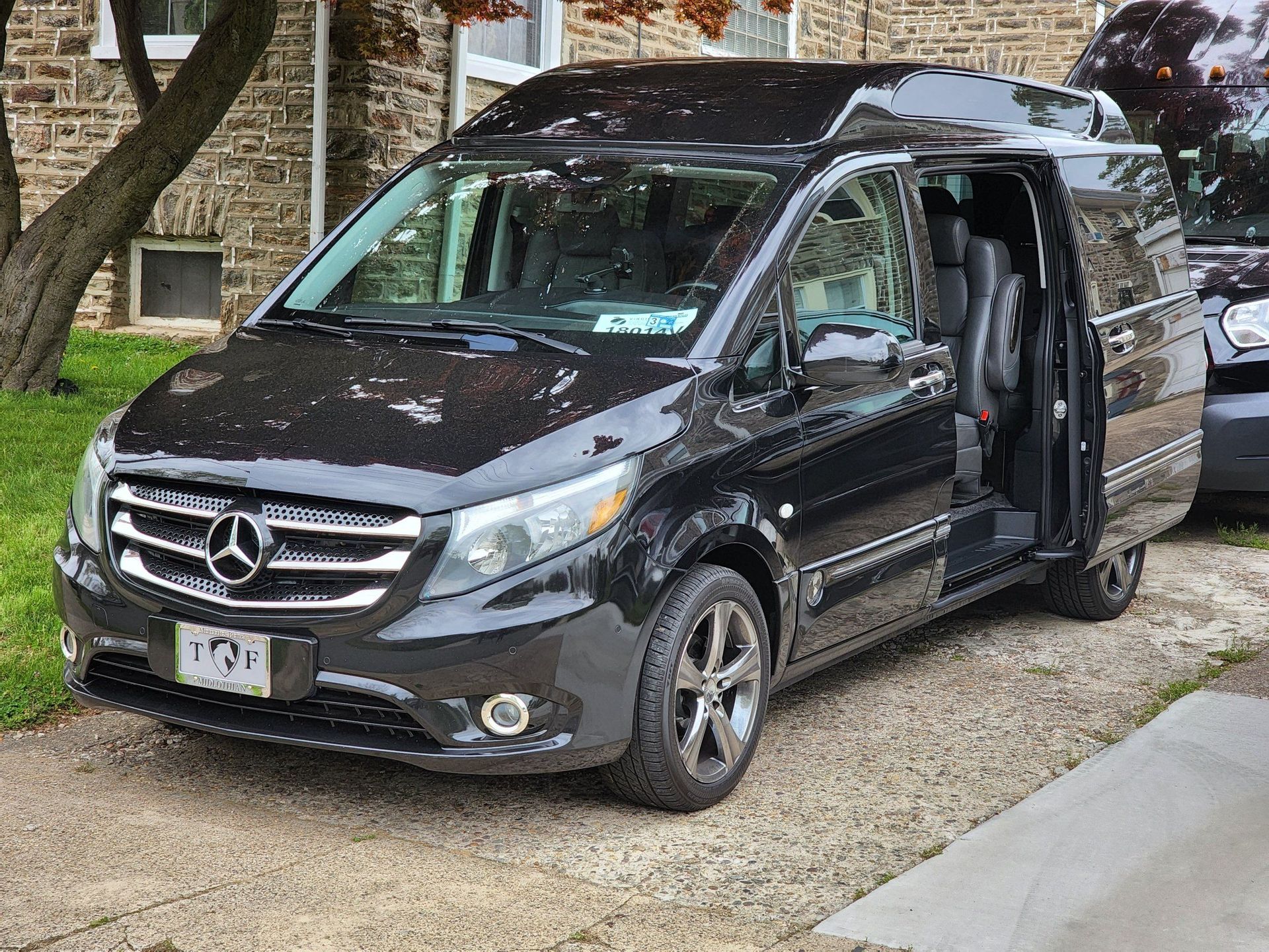 A black mercedes van is parked in front of a brick building.