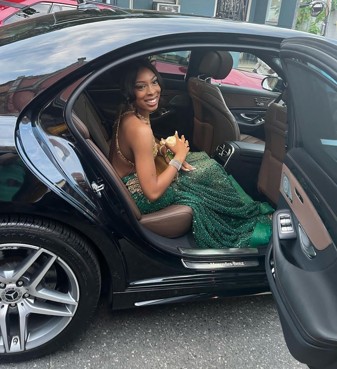 A woman in a green dress is sitting in a black car