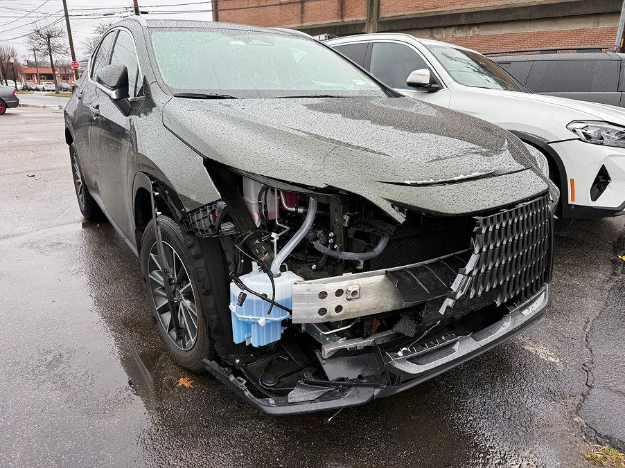 A damaged olive green SUV missing its front bumper and headlight, parked in a lot on a rainy day. | Big n' Littles Auto Body