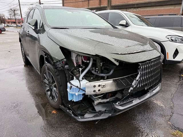 A damaged olive green SUV missing its front bumper and headlight, parked in a lot on a rainy day. | Big n' Littles Auto Body