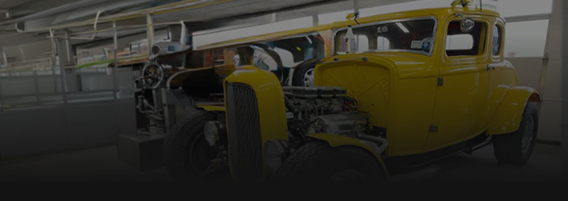 A yellow hot rod coupe parked inside a garage workshop. | Big n' Littles Auto Body