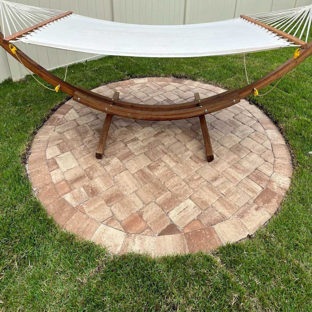 A hammock is sitting on top of a brick patio.