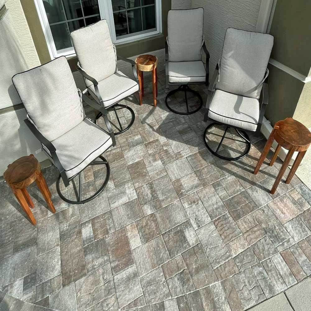 A patio with three chairs and two tables on it