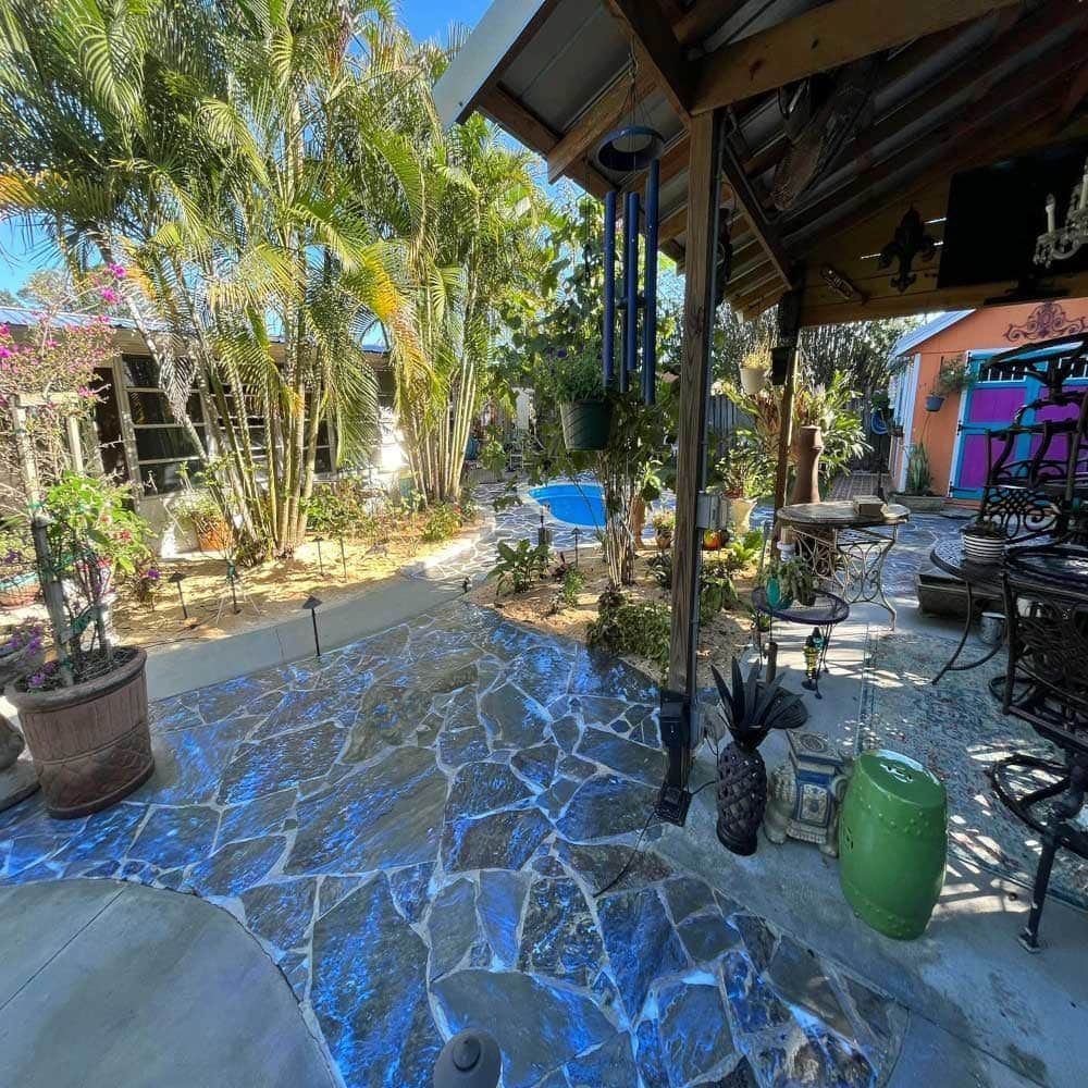 A patio with a covered area and a swimming pool in the background.