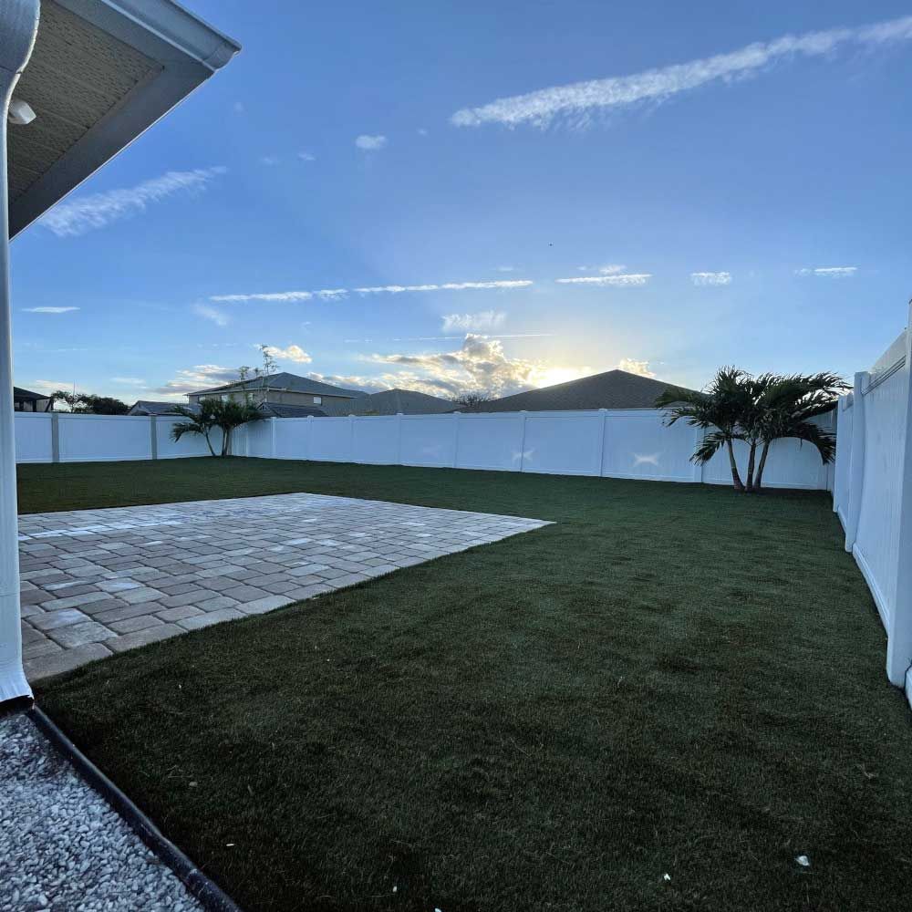 A backyard with a white fence and a lot of grass