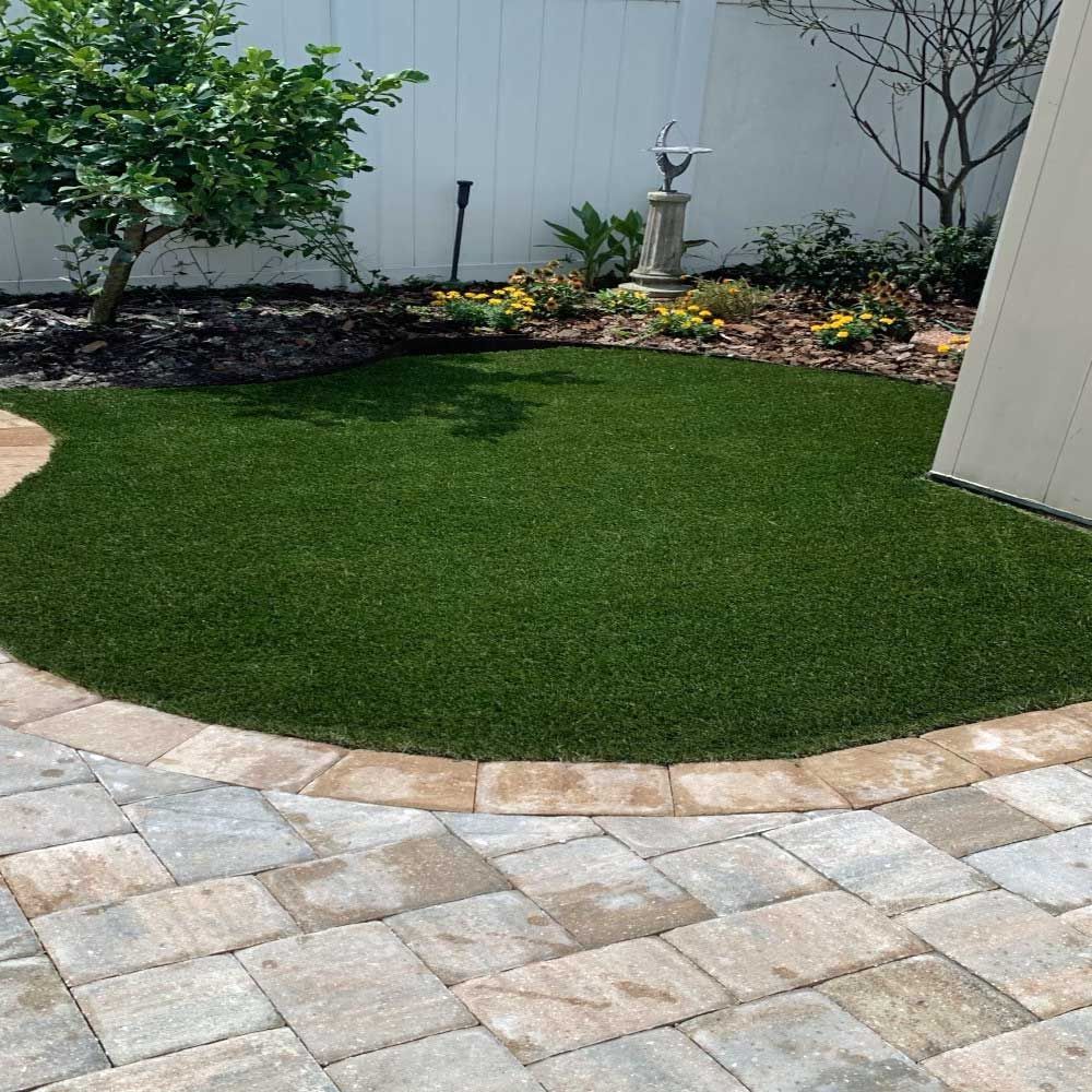 A patio with a circle of grass and a bird bath