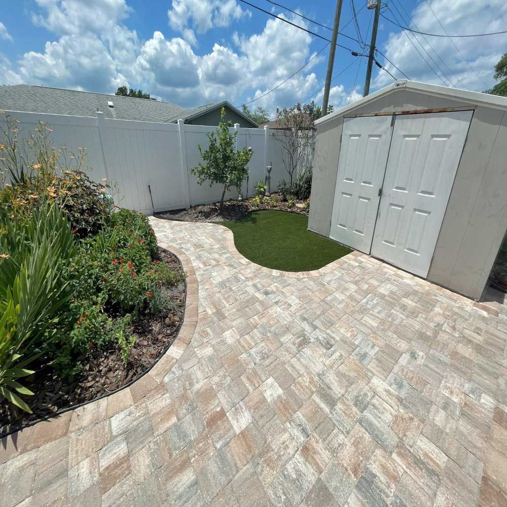 A brick walkway leading to a shed in a backyard.
