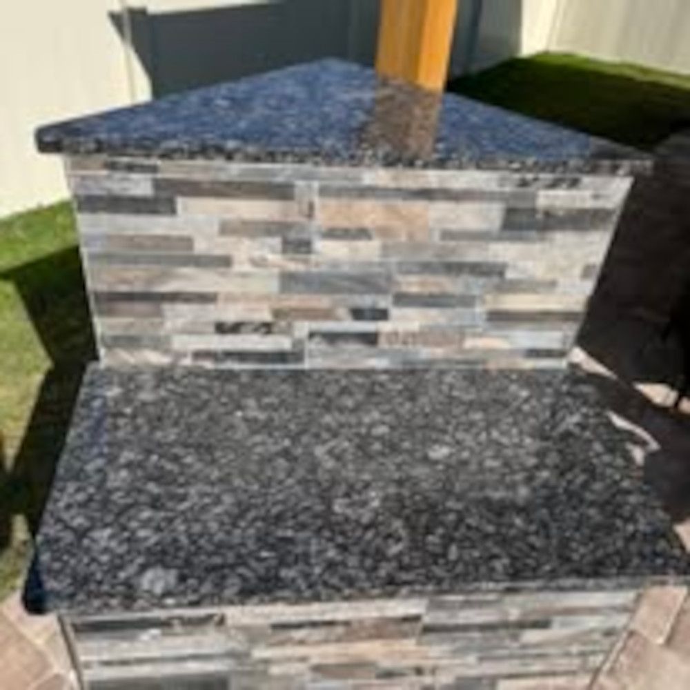 A black granite counter top is sitting on top of a brick wall.
