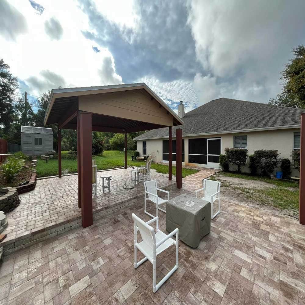 A patio with a gazebo and chairs in front of a house