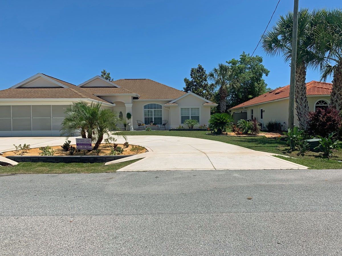 A white house with a driveway and palm trees in front of it