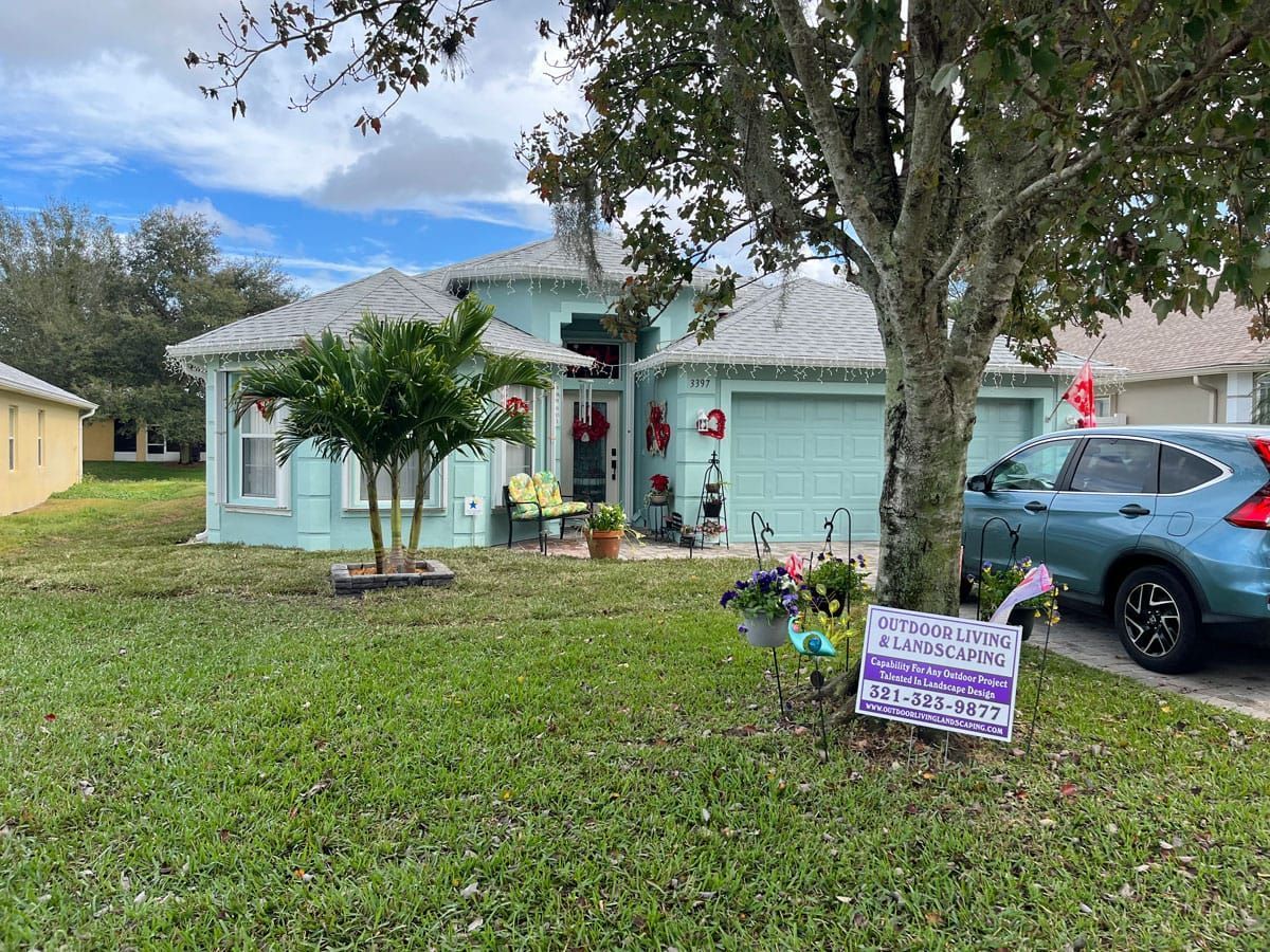 A house with a car parked in front of it and a sign in front of it.