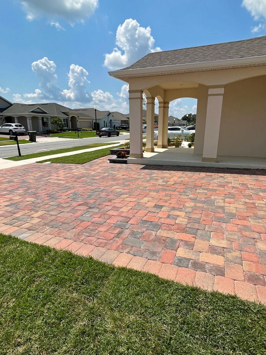 There is a brick driveway in front of a house.