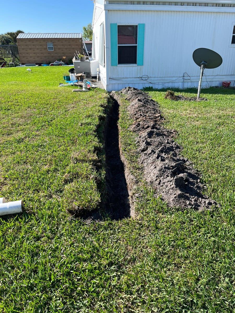 A large hole in the grass in front of a mobile home.