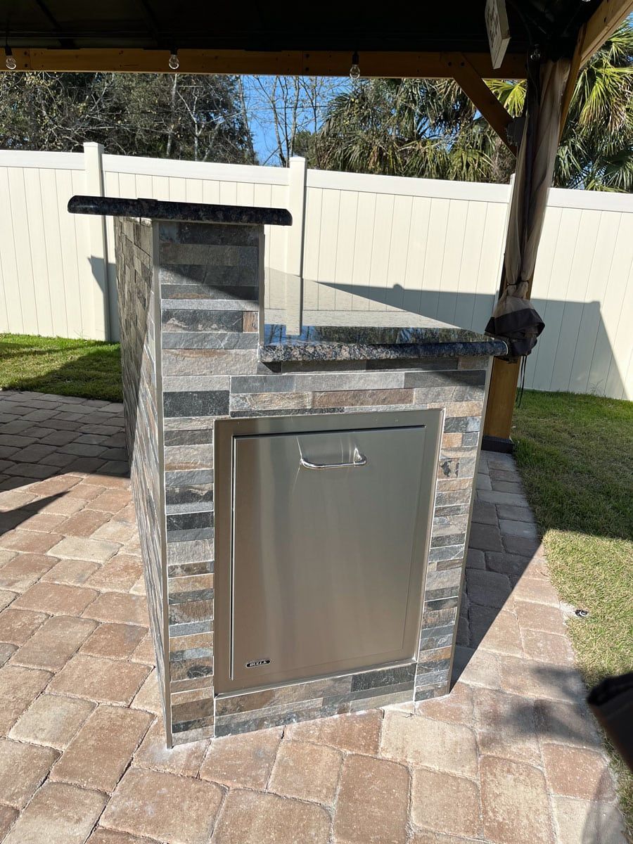 A brick and stainless steel outdoor kitchen with a stainless steel door.