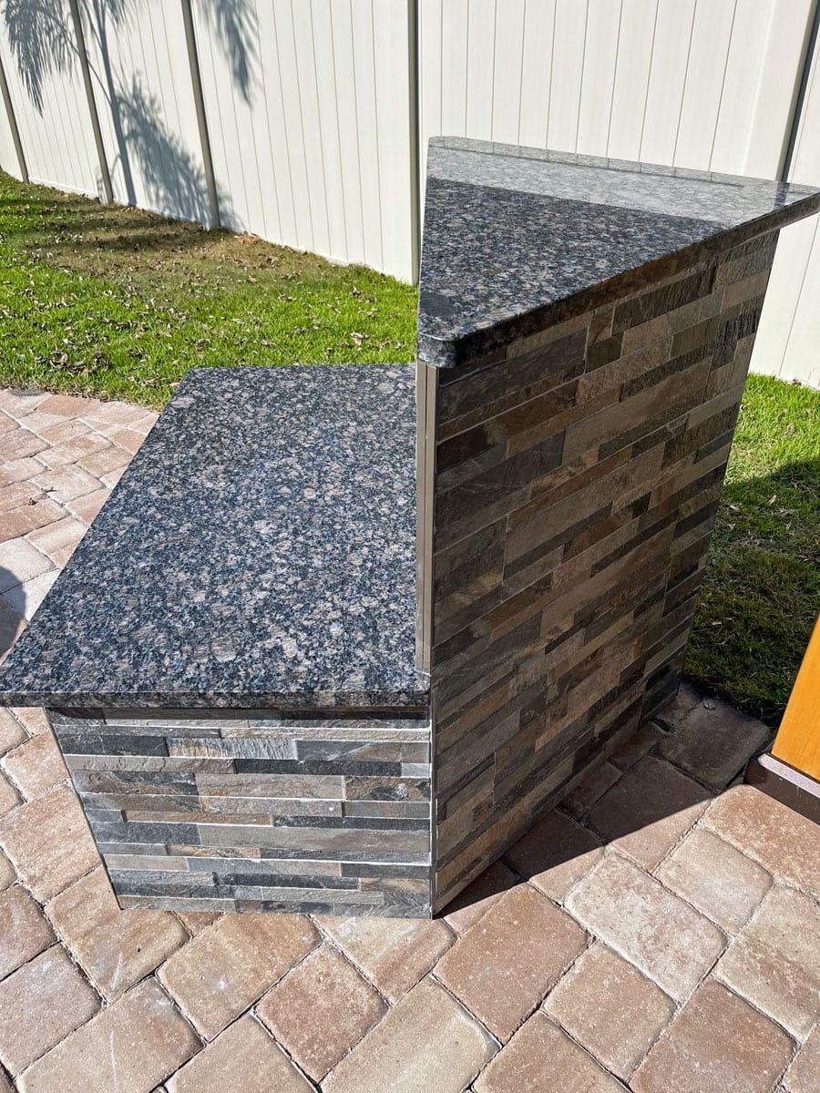 A granite counter top is sitting on top of a brick patio.