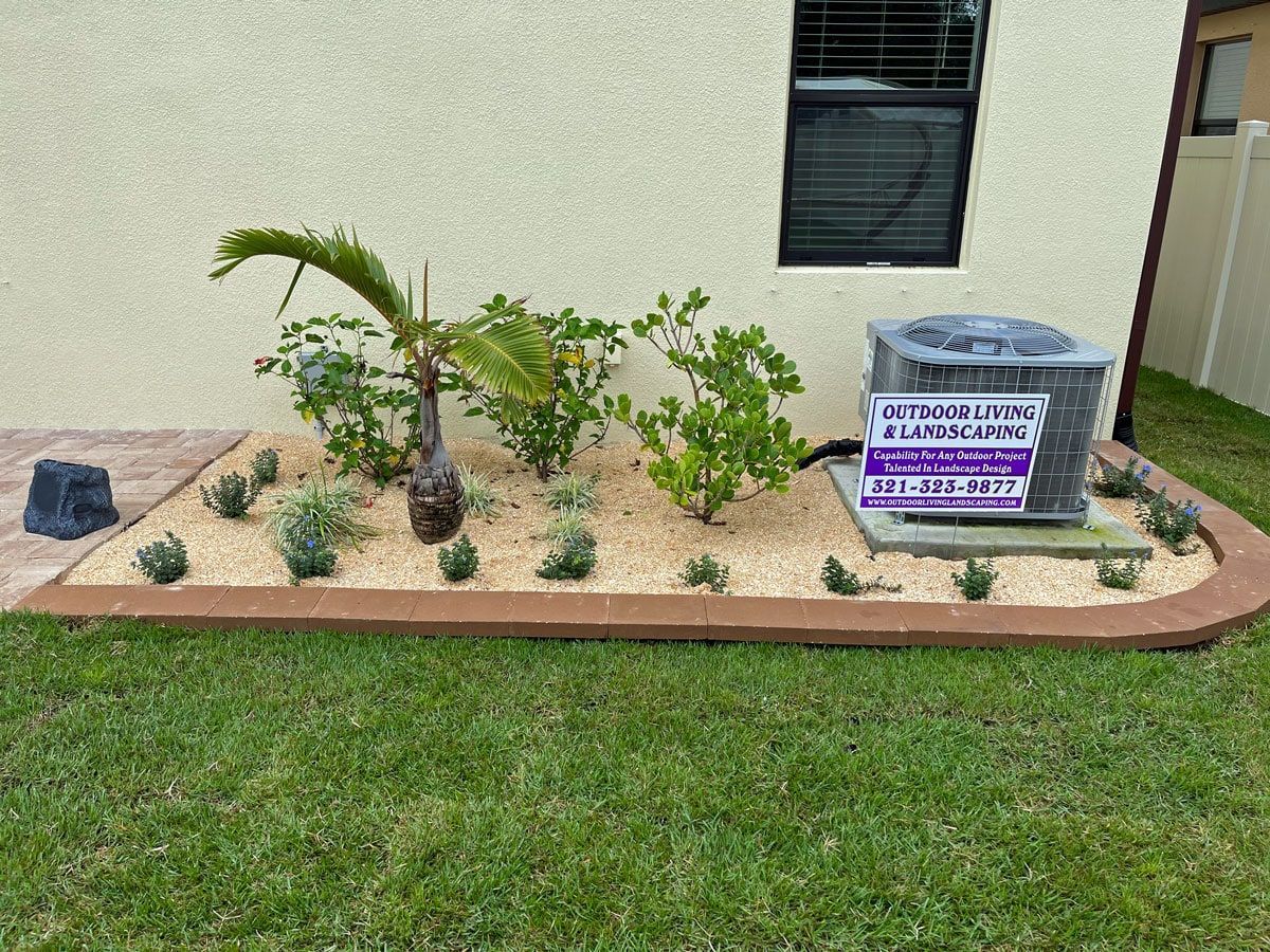An air conditioner is sitting in a garden next to a house.