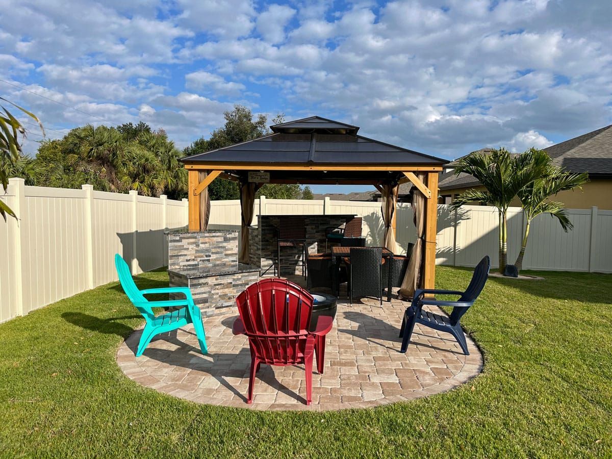 A gazebo with a fire pit and chairs in a backyard.