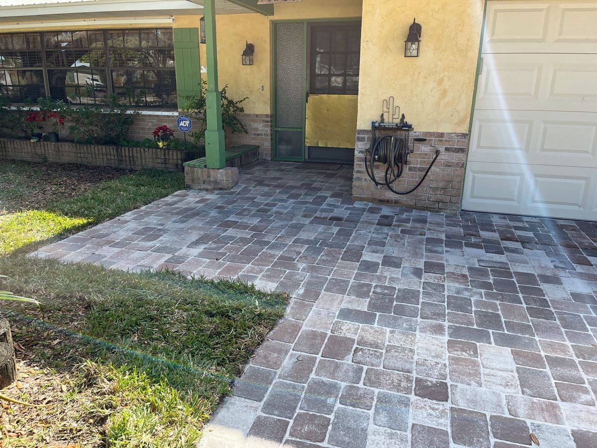 A brick walkway leading to a house with a garage door.