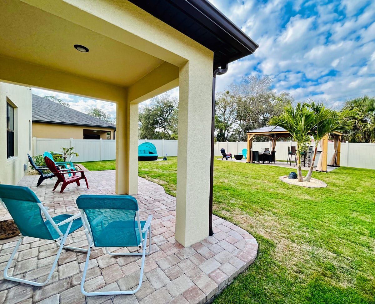 A patio with chairs and a gazebo in the backyard of a house.