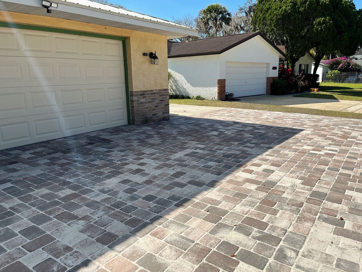 A brick driveway leading to a garage and a house.