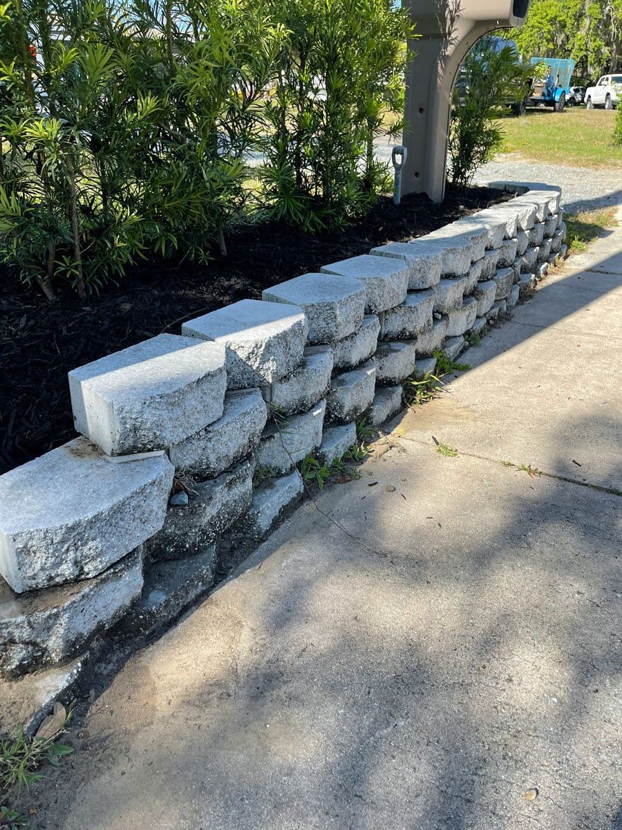 A stone wall along a sidewalk next to a mailbox.