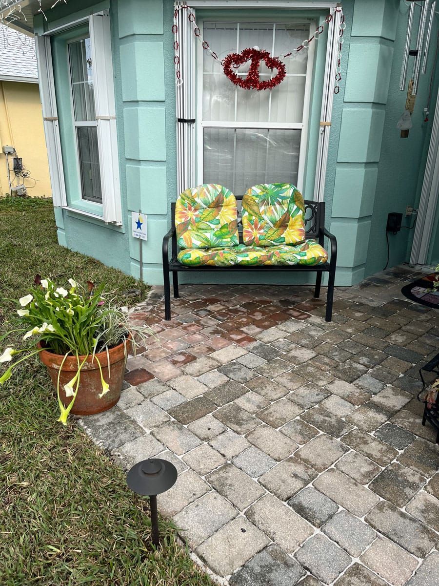 A patio with a bench and a potted plant in front of a house.