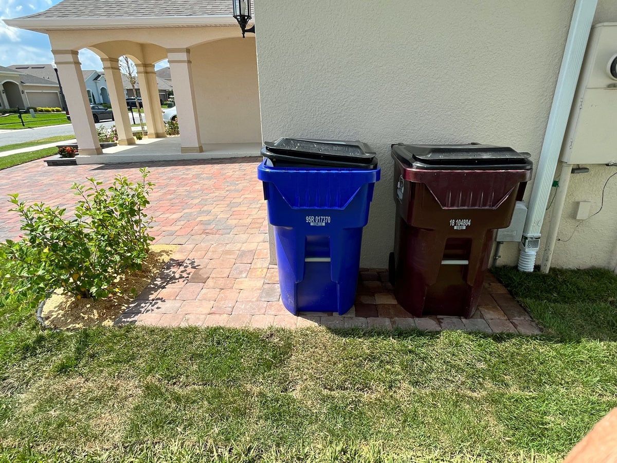 Two trash cans are sitting next to each other on the side of a house.