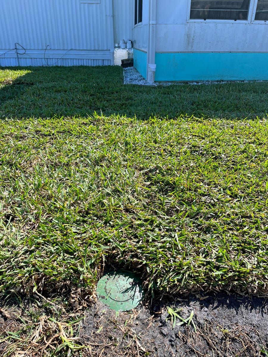There is a hole in the grass in front of a house.