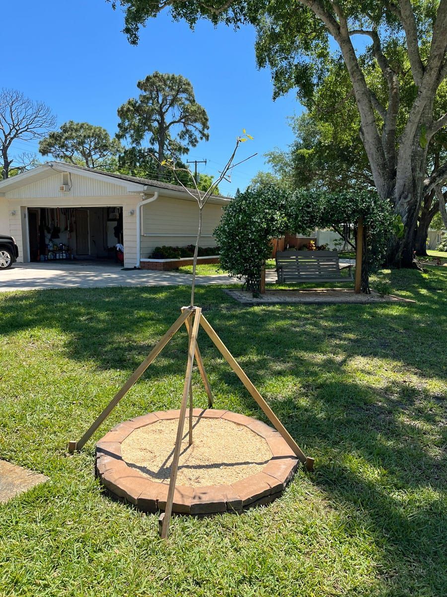 A wooden tripod is sitting in the grass in front of a house.
