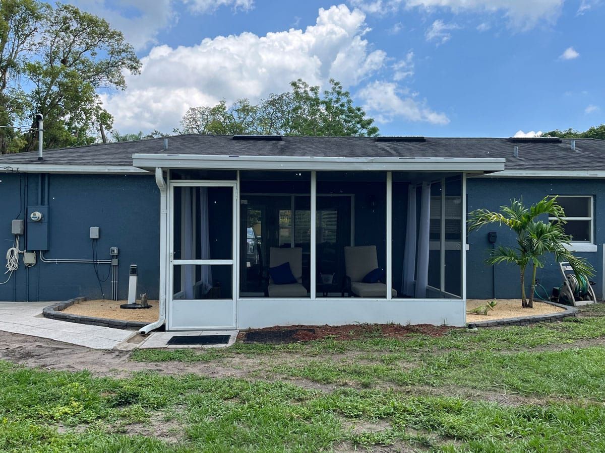 A blue house with a screened in porch in the backyard.