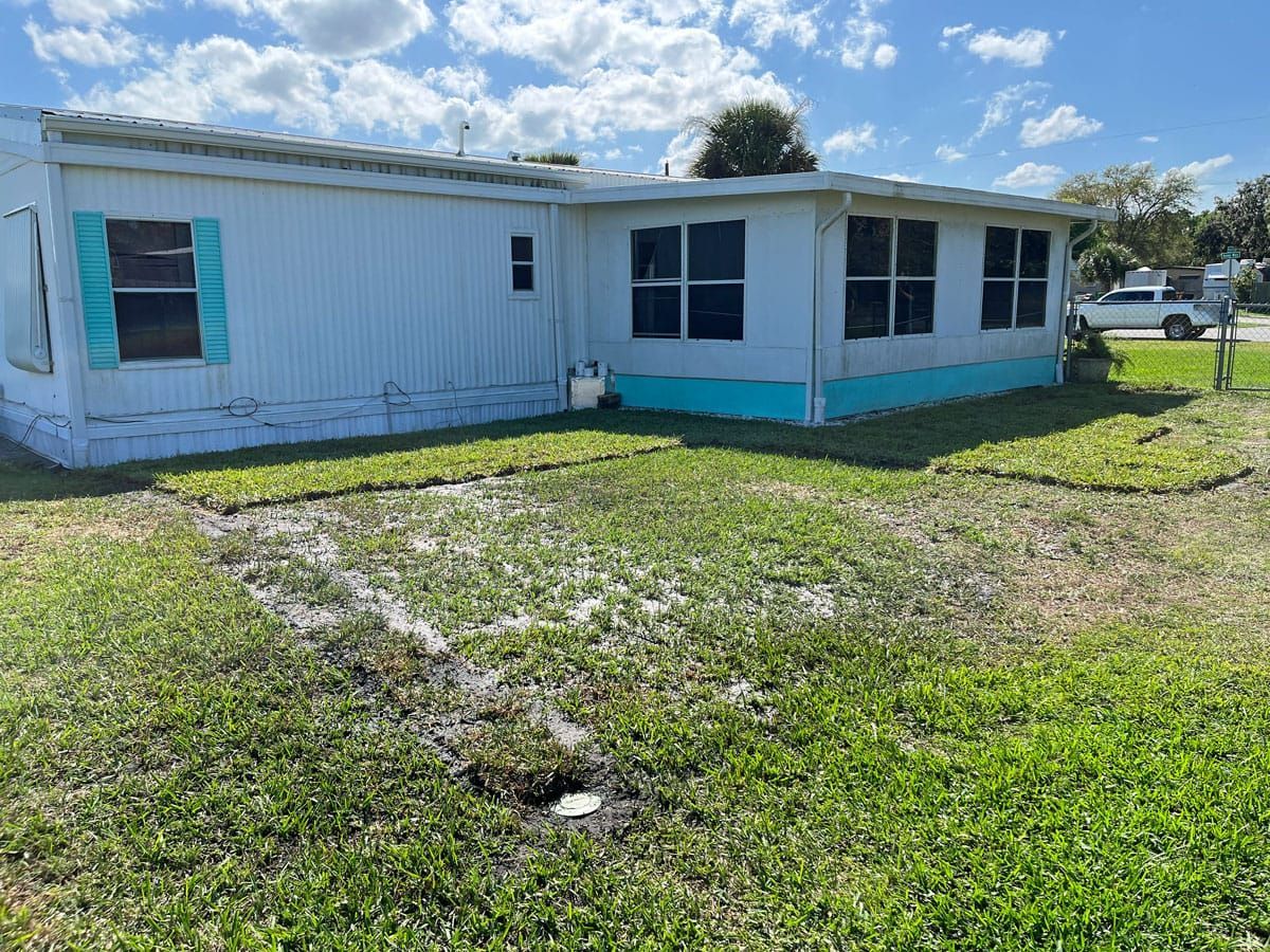 A mobile home is sitting in the middle of a lush green field.