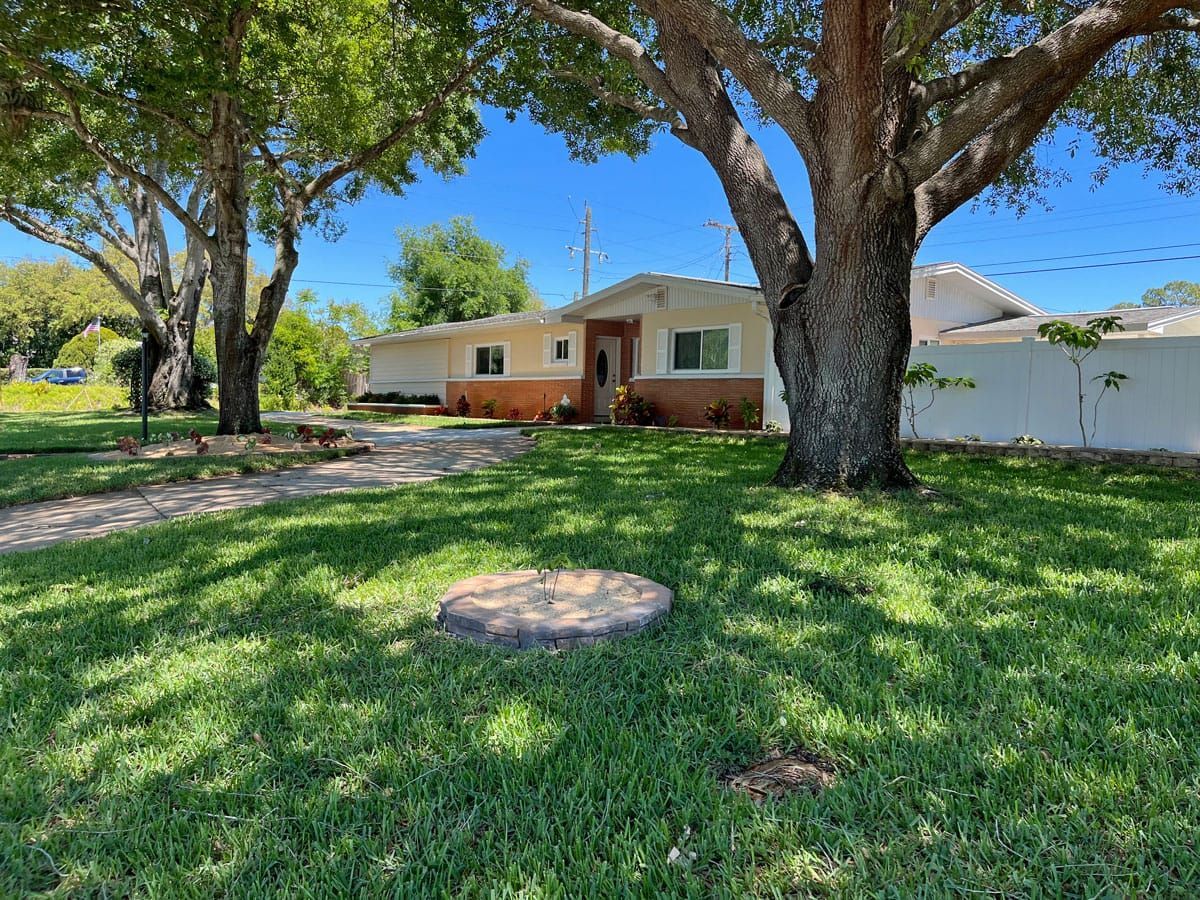 A house with a large lawn and trees in front of it.