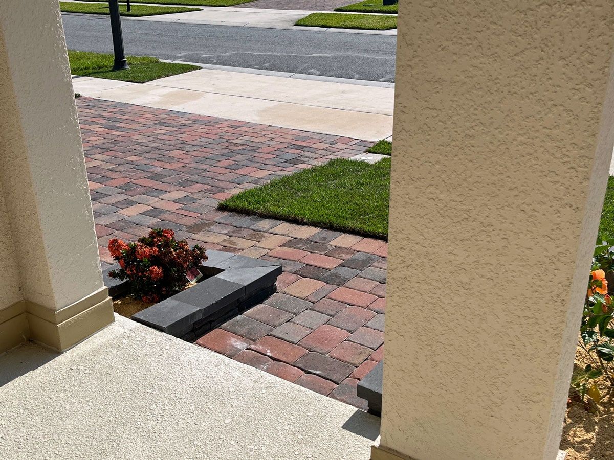 A view of a brick driveway from a porch of a house.