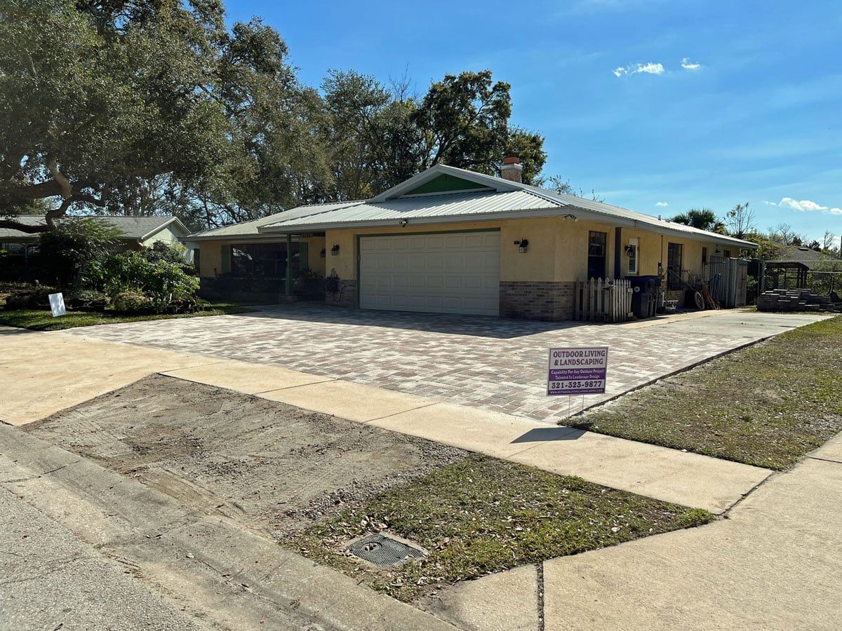 A house with a large driveway and a sign in front of it.