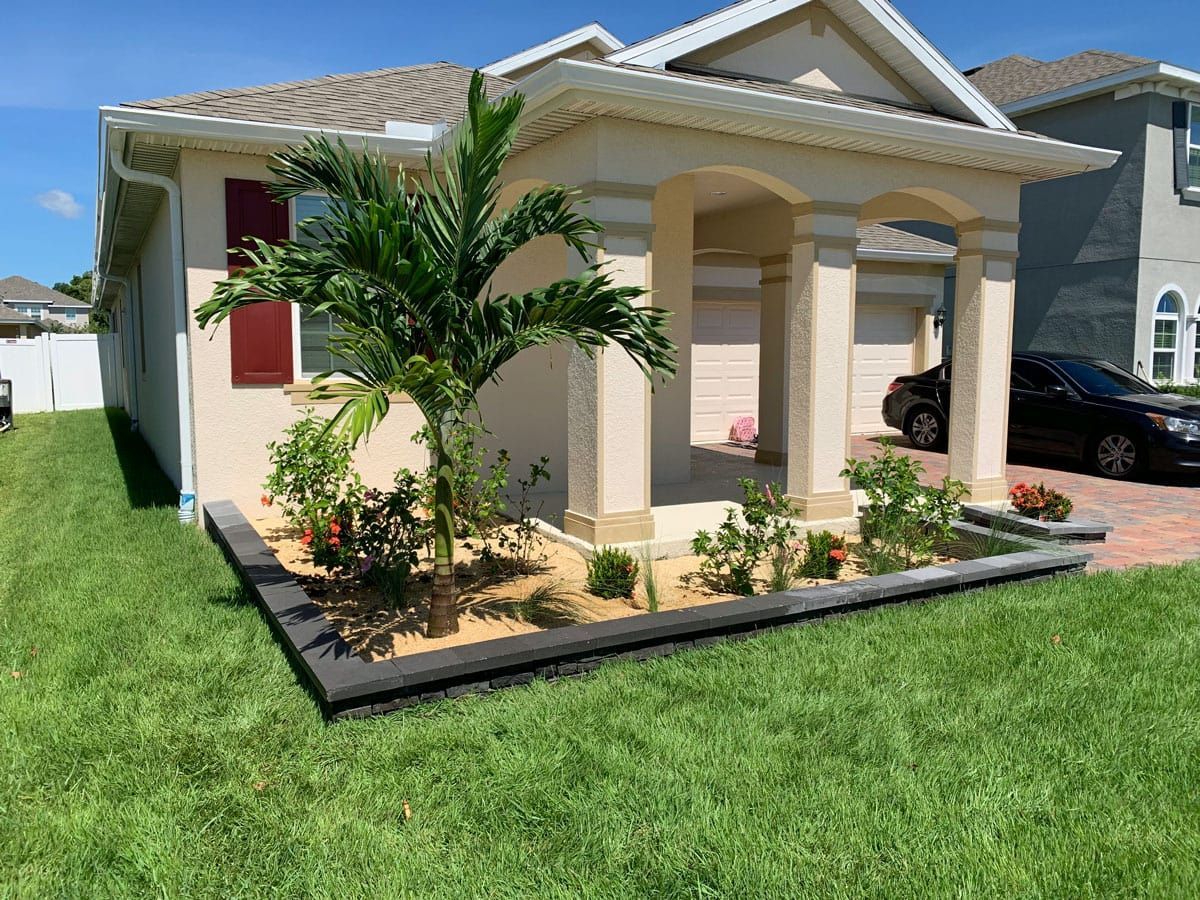 A house with a car parked in front of it and a lush green lawn.