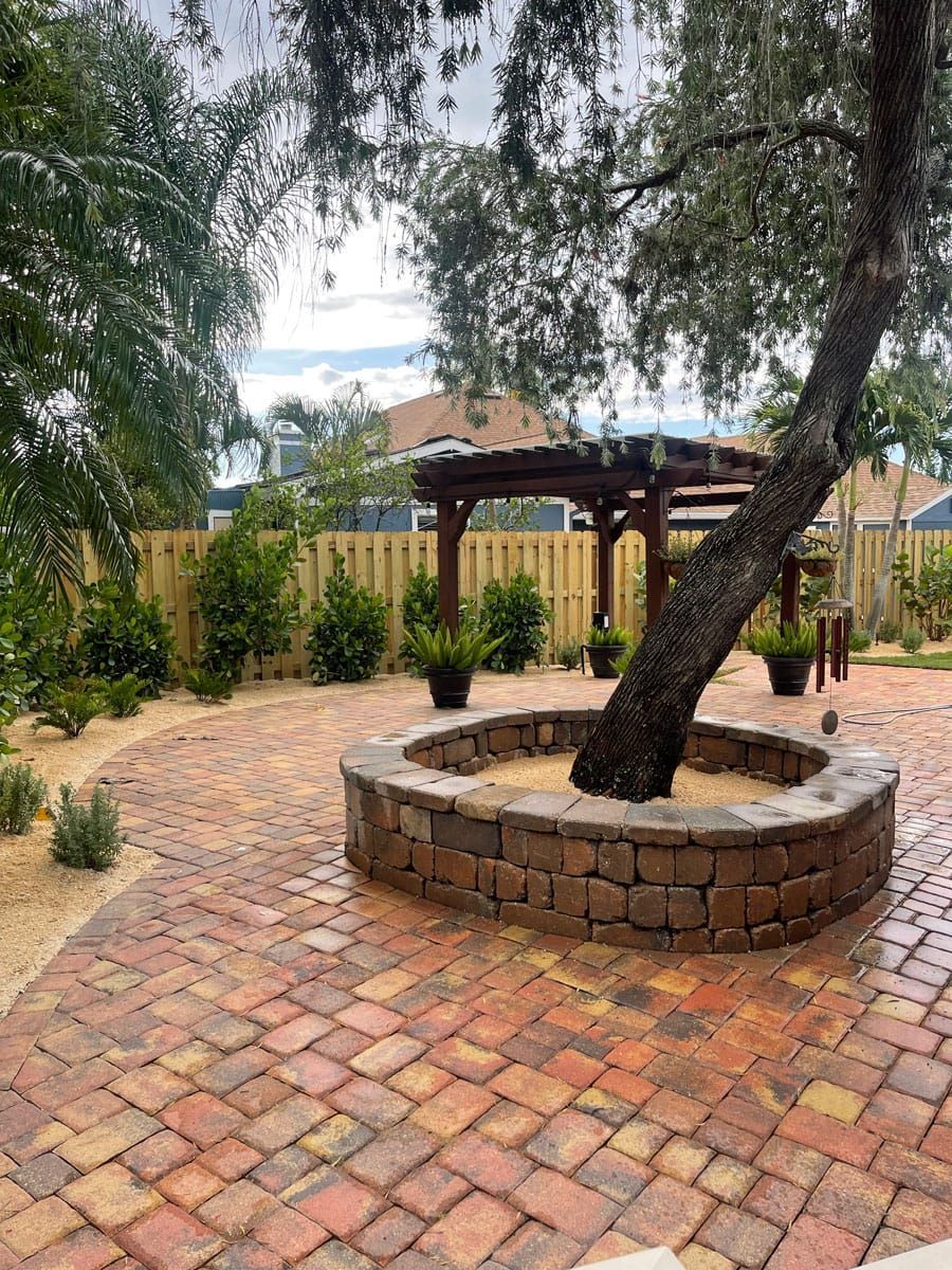 There is a tree in the middle of a brick patio.