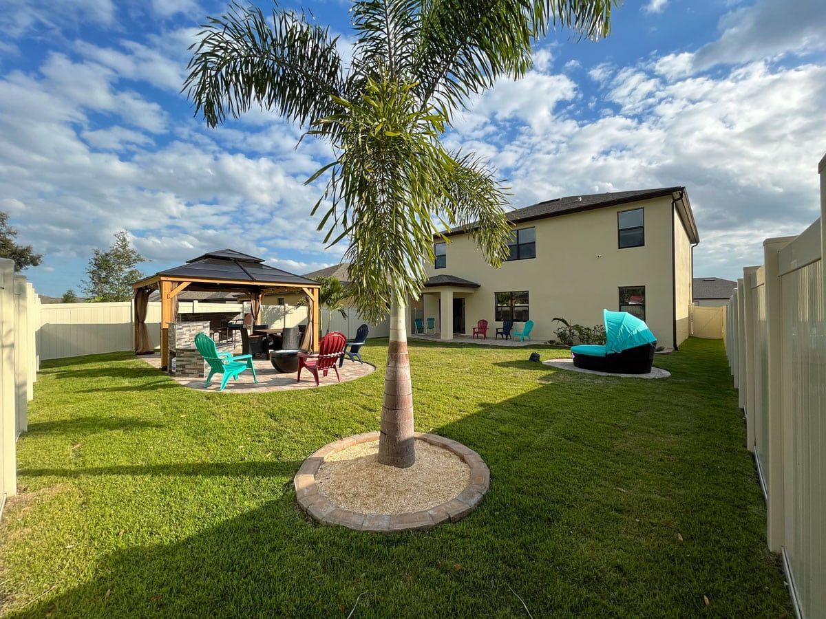 A backyard with a gazebo , chairs , and a tree.