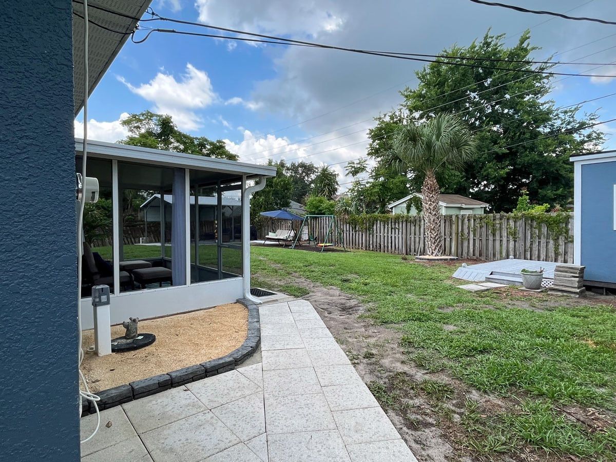 A house with a screened in porch and a fence in the backyard.